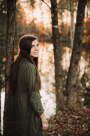 teen girl looks at the camera while standing in front of a lake