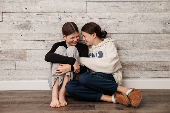 teen sisters laugh together while sitting on the floor