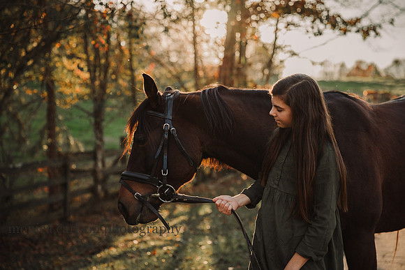 teen girl looks at her horse at sunset