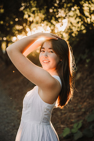 back lit teenaged girl with her arms above her head