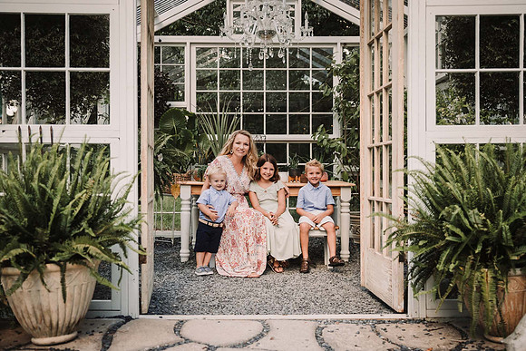 mom sits with her three kids in a greenhouse