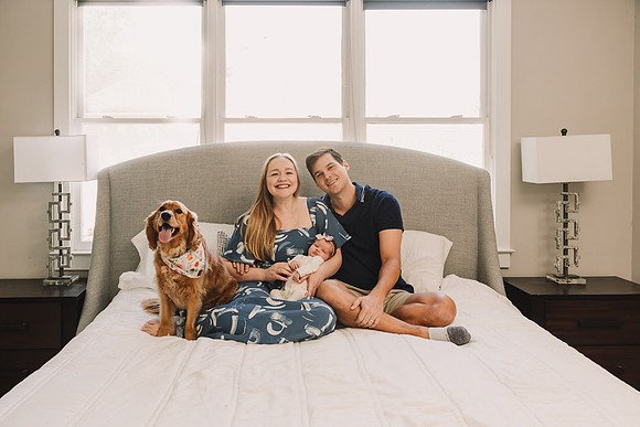 Young couple on bed with dog and newborn baby