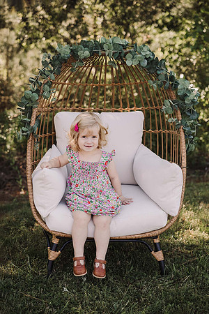 Toddler girl sits in a egg chair for school portraits