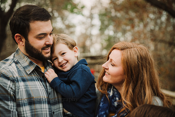 mother and father cuddle their three year old son