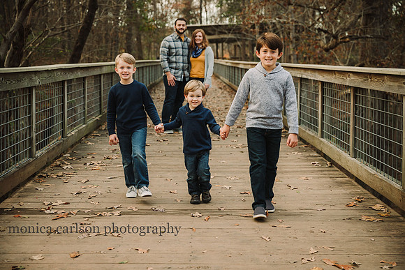 three brothers walk hand in hand while their parents watch on the bridge at McDaniel Family Farm