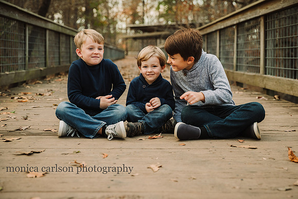 three brothers giggle together during a mini session on a bridge
