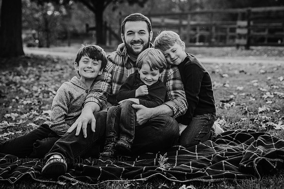father snuggles with his three young sons during a photo session with monica carlson