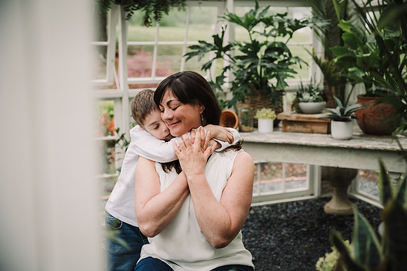 Mom gets a hug from her son sitting in a greenhouse