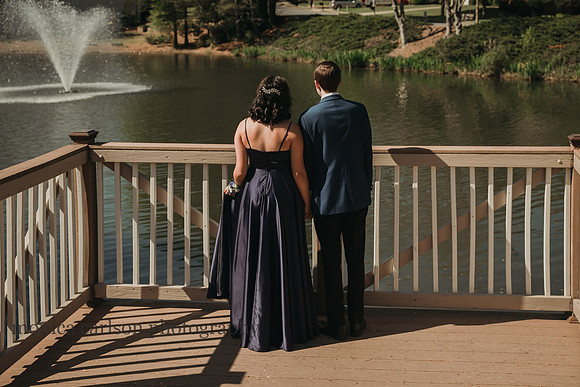 drressed up young couple look out over a lake before their first prom