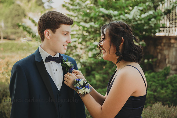 young woman puts a boutonniere on her prom date by monica carlson