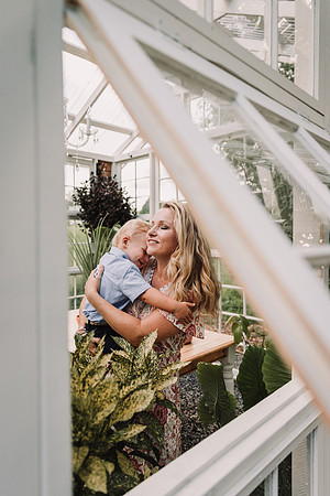 view of mom getting a hug from little son in a green house