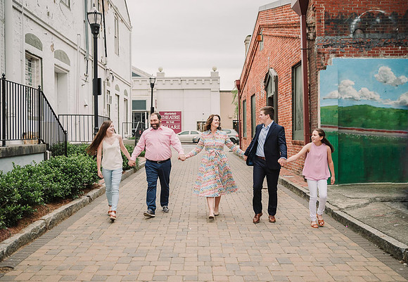 family of five walking hand in hand down a brick road in a older area of marietta, GA