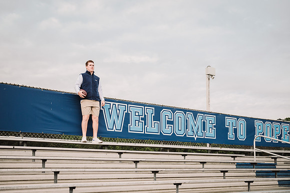 young man holding a football at the stadium at pope high school in marrietta, ga