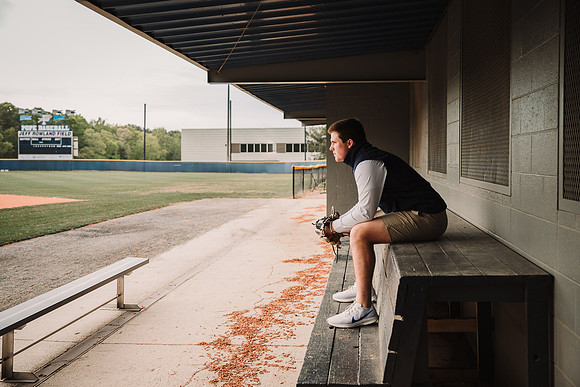 Senior boy sitting in the dug out at Pope High school's stadium