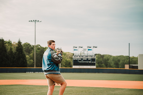 senior  boy throwing a ball at the baseball field during a senior photo session by monica carlson