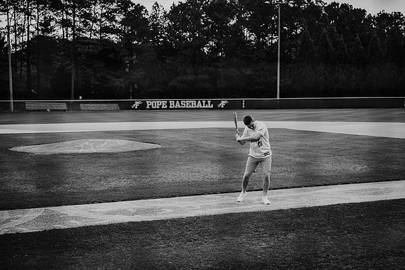 young man swinging a bat during his senior photo session by monica carlson