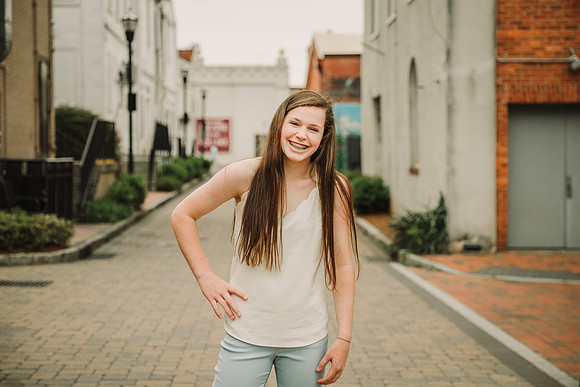 Teen girl laughing on a street in Marietta Square during a family photo session with monica carlson