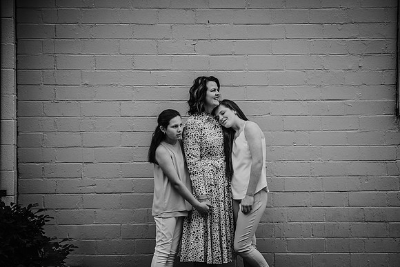 Mother cuddling her teen daughters during a family photo session
