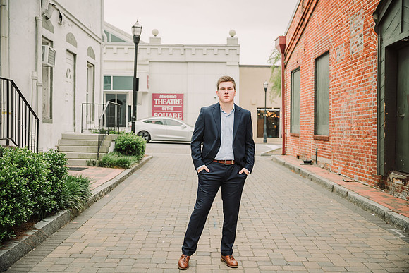young man wearing a suit while standing in the middle of a brick road in Marietta Square