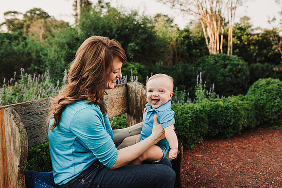 adorable smiling baby siting on his moms lap in a garden by monica carlson photograhy