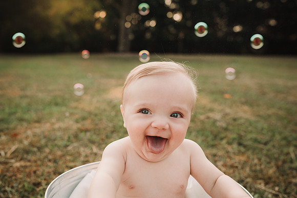 portrait of a very happy baby with back lit bubbles in the back ground