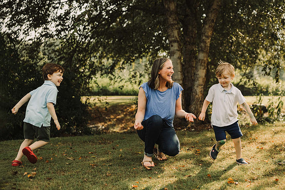 mother laughs while her toddlers run around her