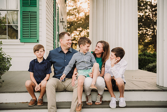 family of five laughing together on a pation in roswell during a photo session
