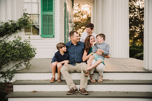 family of five laughing together on the patio of Barrington hall in Roswell