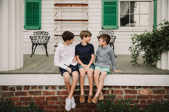 three brothers laughing together on the patio of a historic home