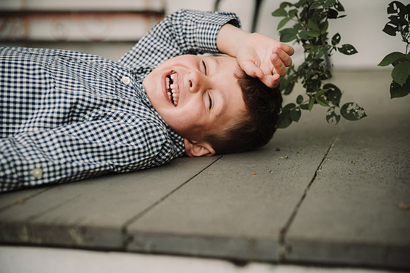 toothless litlle boy laughs so hard he lays down