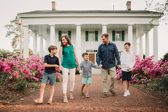 sprintime image of a family walking by azeleas bushes with historic barrington hall in the back ground