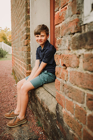 Smirking young boy sitting in a dorrframe during a family photo session