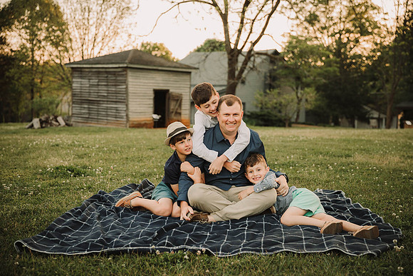 father snuggles his three sons on a blanket in roswell, GA