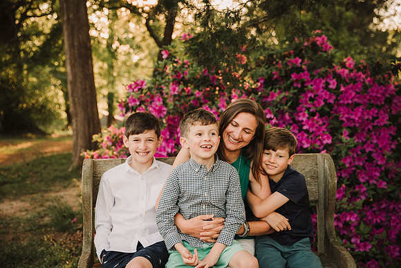 mother shares a laugh with her three sons in front of a azelea bush