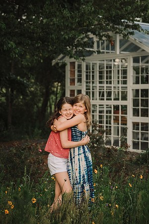 sister happily hig on a field of flowers by a greenhouse at Prospect farms