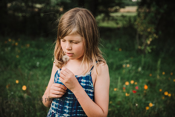 yound girl closes her eyes before blowing a dandelion by monica carlson