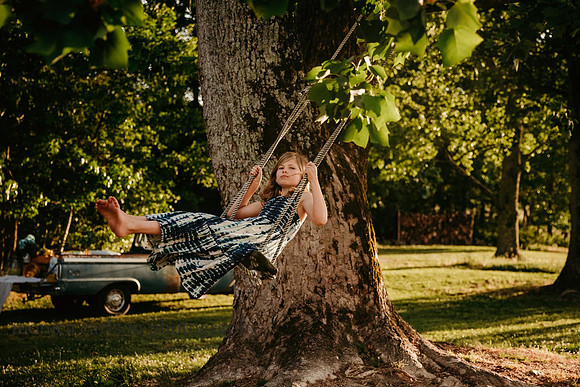 girl on a tree swing with a antique truck in the background