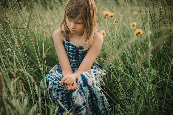 blonde girl sits in a wildflower field by monica carlson