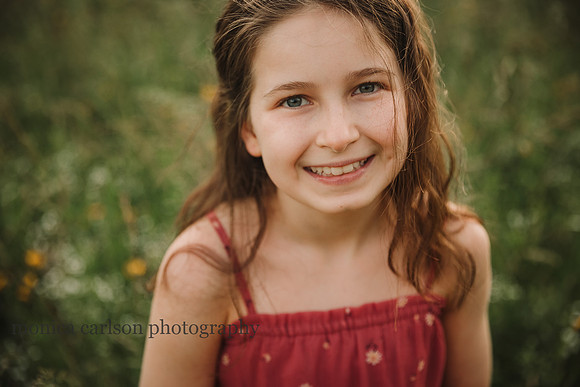 portrait of a smiling girl on a wildflower field by monica carlson photography