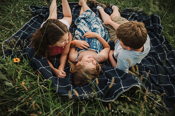 siblings laying together on a blanket in a field at prospect farms