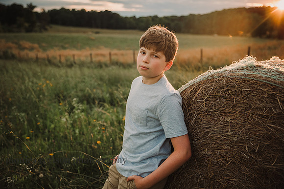 backlit image of a serious teen boy leaning on a hay bale at prospect farms