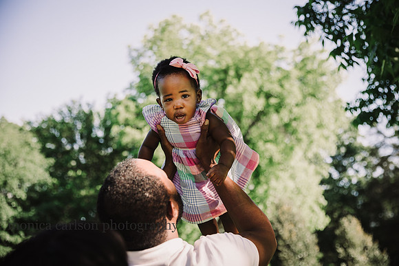 african american baby being held above her parents heads