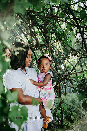 mother holds her baby girl happily in a grape vine tunnel during a photo session in Roswell, GA with Monica carlson photography