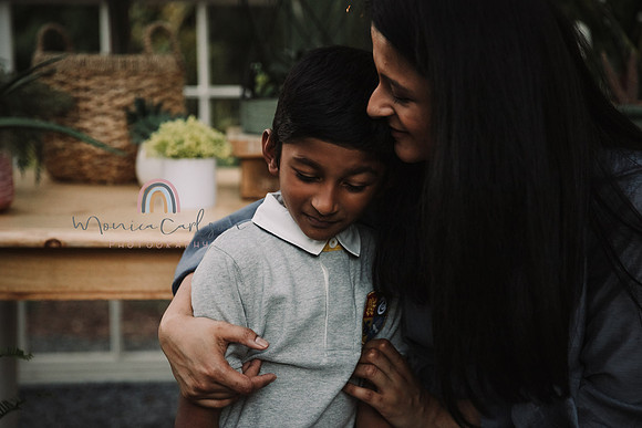 mom and son share a tender moment in a greenhouse during a photo session with monica carlson