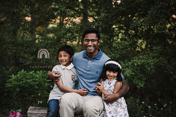 dad smiles with his children while they sit on a bench near a wooded area in Lawernceville, GA
