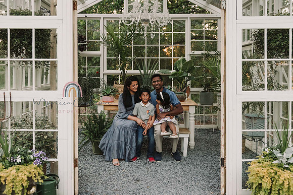 Indian family of four snuggle in a greenhouse during a family photo session