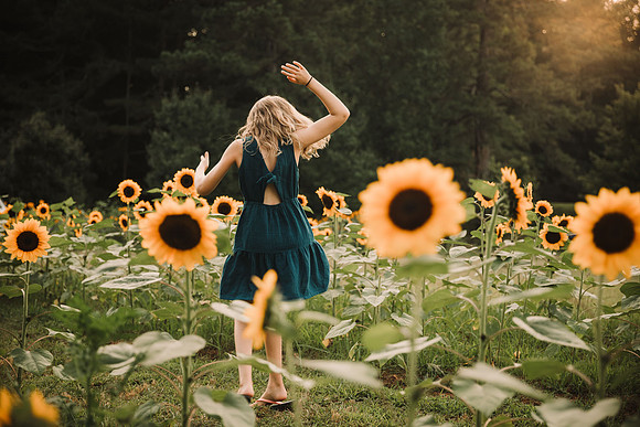 tween girl spinning on a sunflower field at sunset by monica carlson photography