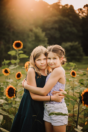 sisters hugging amoung sunflowers at sunset in Milton, GA