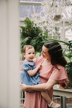 mom holding her baby in a greenhouse