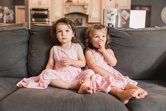 twin preschool sisters sitting on a couch in their living room during a family photo session